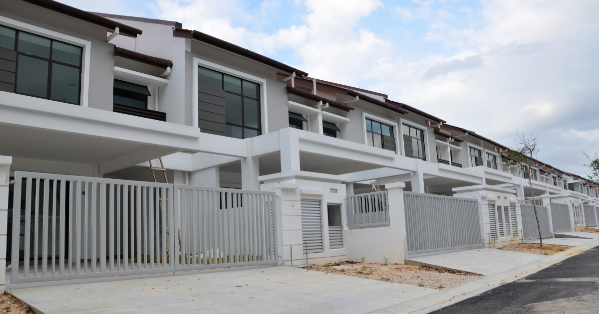 A row of newly built, modern double-story terrace houses with gray gates lines a residential street