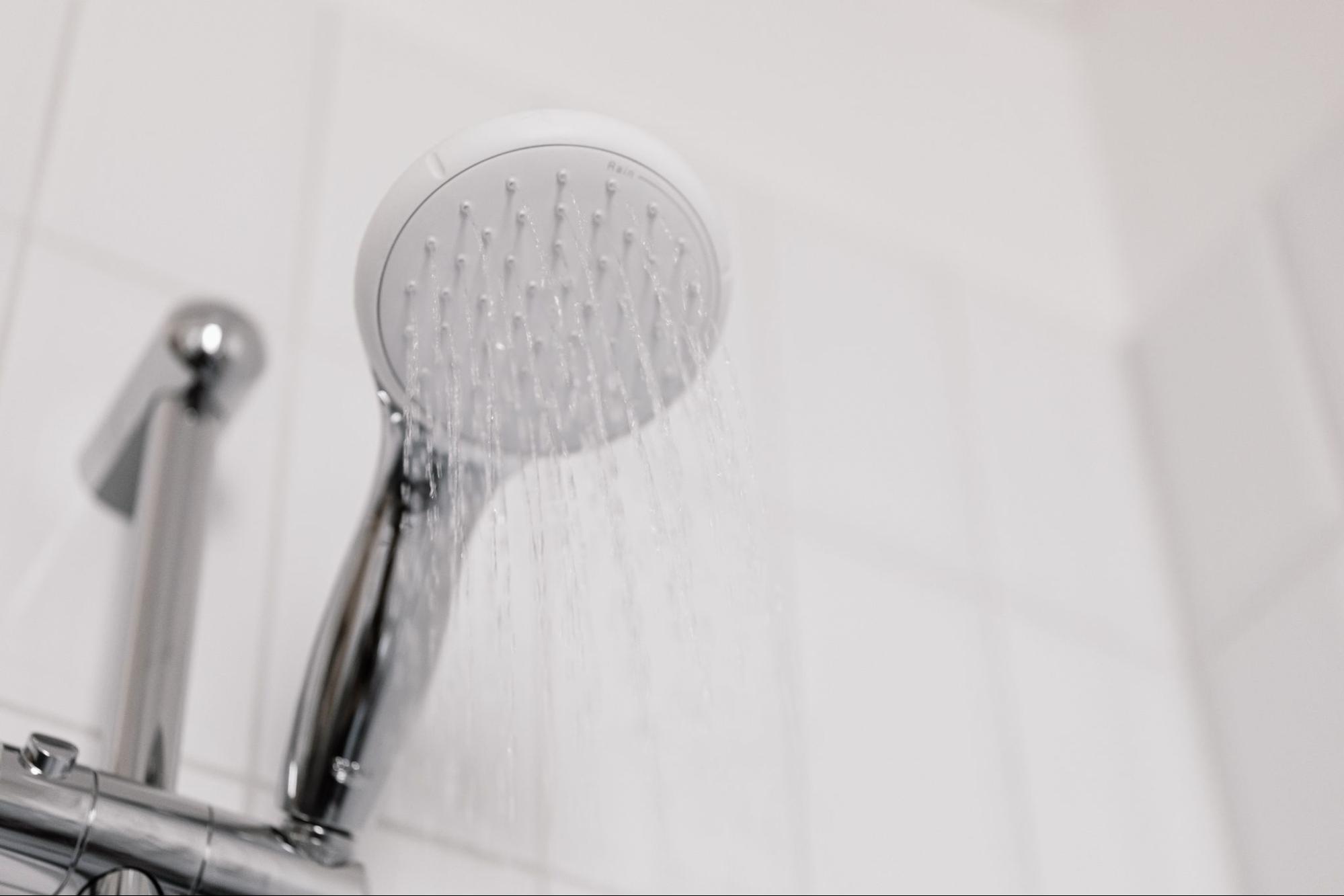 A handheld showerhead sprays water in a bathroom